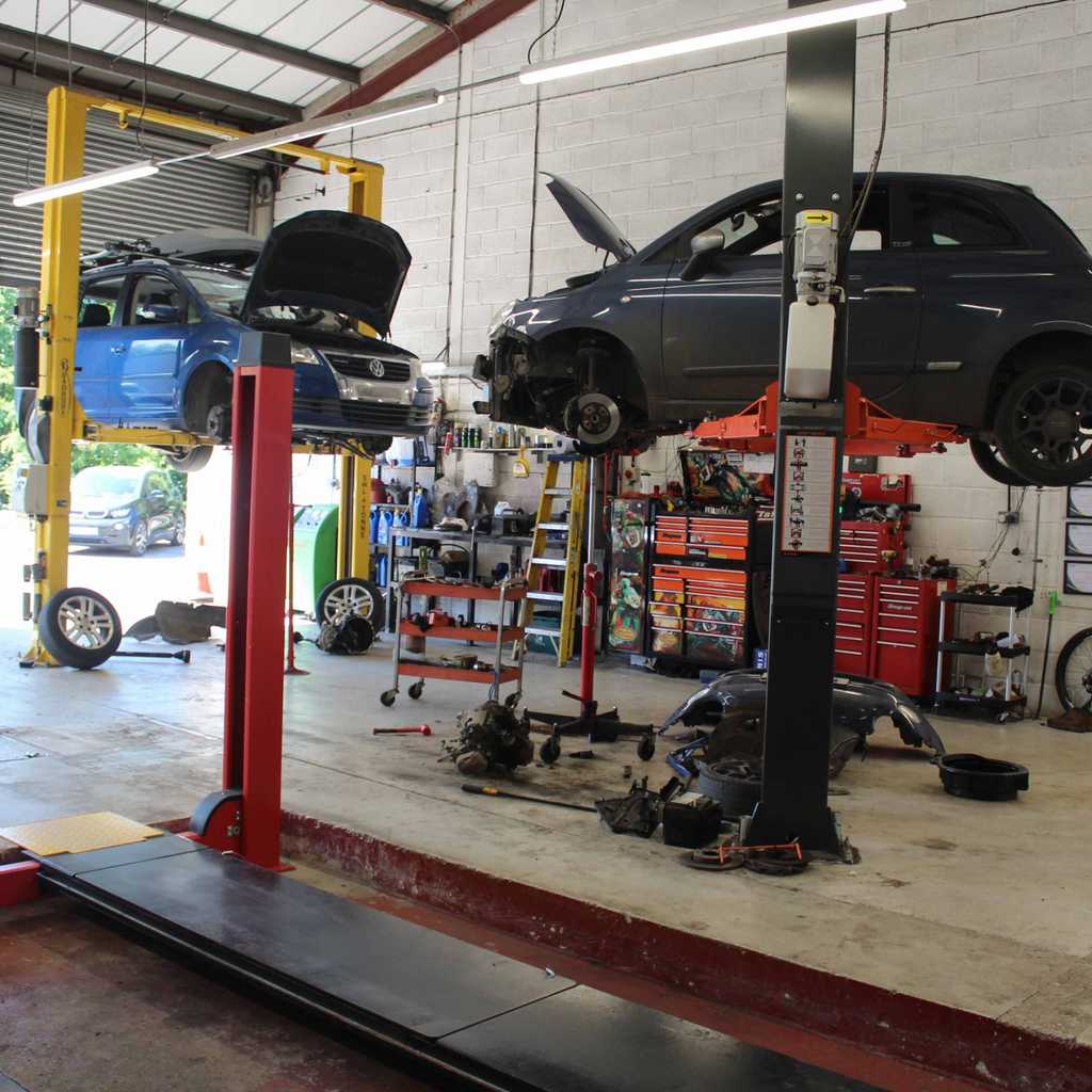 A car suspended in the air with a mechanic ready to work on it